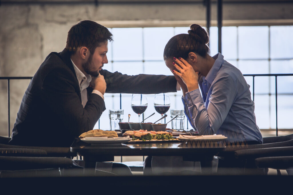 Young couple in restaurant at lunch break. She is sad, about to cry